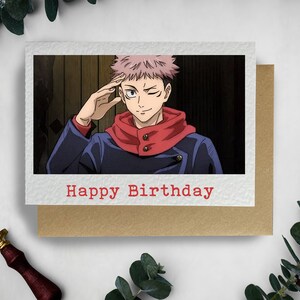 May include: A birthday card featuring an anime character with pink hair, wearing a blue jacket and red scarf, with the text "Happy Birthday" in red.