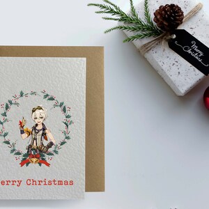 May include: A Christmas card featuring a cartoon character with blonde hair and a red and green holly wreath. The card has the text "Merry Christmas" in red.