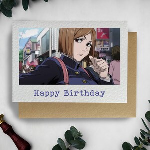 May include: A birthday card with a photo of an anime character with brown hair and a blue uniform. The text "Happy Birthday" is printed on the card.