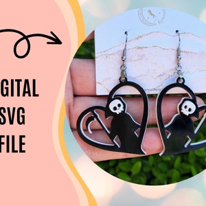 May include: A pair of black heart-shaped earrings with a silhouette of the Grim Reaper holding a scythe inside each heart. The earrings are on a white card with the text "Dream and Believe".