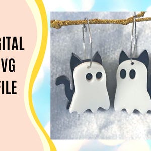 Könnte beinhalten: Weiße und schwarze Geisterkatzen-Ohrringe hängen an einem goldenen Ast. Die Ohrringe haben die Form eines Geistes mit Katzenohren und einem Schwanz. Der Text "DIGITAL SVG FILE" ist auf der linken Seite des Bildes zu sehen.