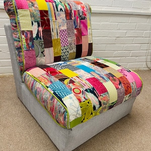 May include: A contemporary armchair with a patchwork design. The seat and backrest are composed of colourful fabric squares, each with a different pattern, and edged with a lime green trim. The base is a solid grey fabric.