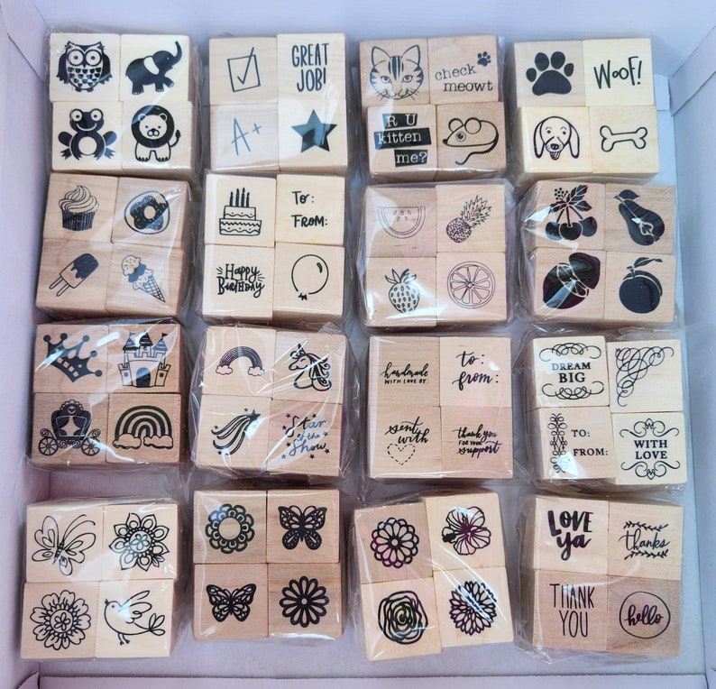 May include: A set of 48 wooden stamps with various designs, including animals, hearts, stars, rainbows, and words like "love", "thank you", and "dream big".