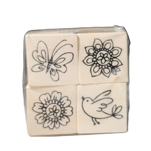 May include: Set of four wooden stamps with black ink designs. The designs include a butterfly, a flower, a bird, and a mandala.