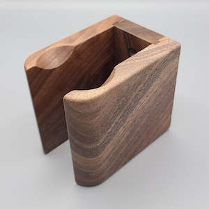 Könnte beinhalten: Eine Wandhalterung aus Holz mit einem geschwungenen Design, perfekt zum Aufbewahren einer Vielzahl von Gegenständen. Die Halterung ist aus dunkelbraunem Holz mit natürlicher Maserung.