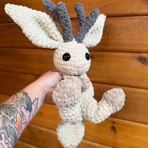 Pu&ograve; includere: Un peluche all'uncinetto fatto a mano a forma di creatura mitica. Il peluche ha grandi orecchie color crema, corna grigie e occhi neri. Il corpo &egrave; color crema e grigio, con una bocca rosa. Il giocattolo &egrave; morbido e strutturato.