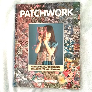 May include: A book titled "Patchwork" with a colourful patchwork cover featuring a young girl holding a patchwork purse. The book cover also includes the text "Over 20 new and original projects for you to make" and the author's name, "Helen Fairfield".