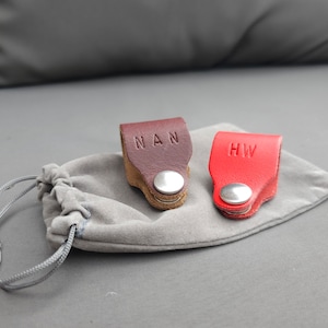 May include: Two leather keyrings with metal rings. One is brown with the initials "NAN" and the other is red with the initials "HW".
