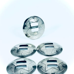 May include: Five silver metal decorative conchos with a starburst design and a rectangular cutout in the center.