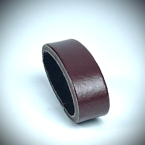 May include: A close-up of a maroon leather ring, showing the smooth texture and the dark brown interior.