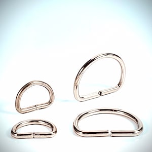 May include: Three silver metal D-rings of different sizes. The rings are open and ready to be attached to a project.
