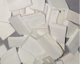 May include: A close-up shot of a pile of white rectangular chalk pieces. The chalk pieces are of varying sizes and shapes, with some appearing broken or chipped. The overall impression is of a collection of art supplies.