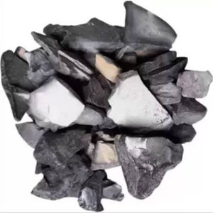 May include: A pile of irregularly shaped rocks in shades of gray, black, and white. Some rocks have a smooth, polished appearance, while others are rough and textured. A few small, light-yellow pieces are interspersed among the darker stones.