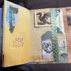 May include: Open journal with decorated pages. Features include a castle illustration, dragon drawings, and handwritten text. The pages are a mix of lined and grid paper, with decorative paper strips and stamps. The color palette includes yellow, blue, and brown.