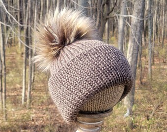 Handgemaakte gebreide muts voor dames en heren in een medium bruine kleur, afgewerkt met een beige/bruine/zwarte/crème pompon.