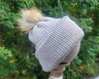 Handgemaakte beige gebreide damesmuts met lichtbruine pompon.