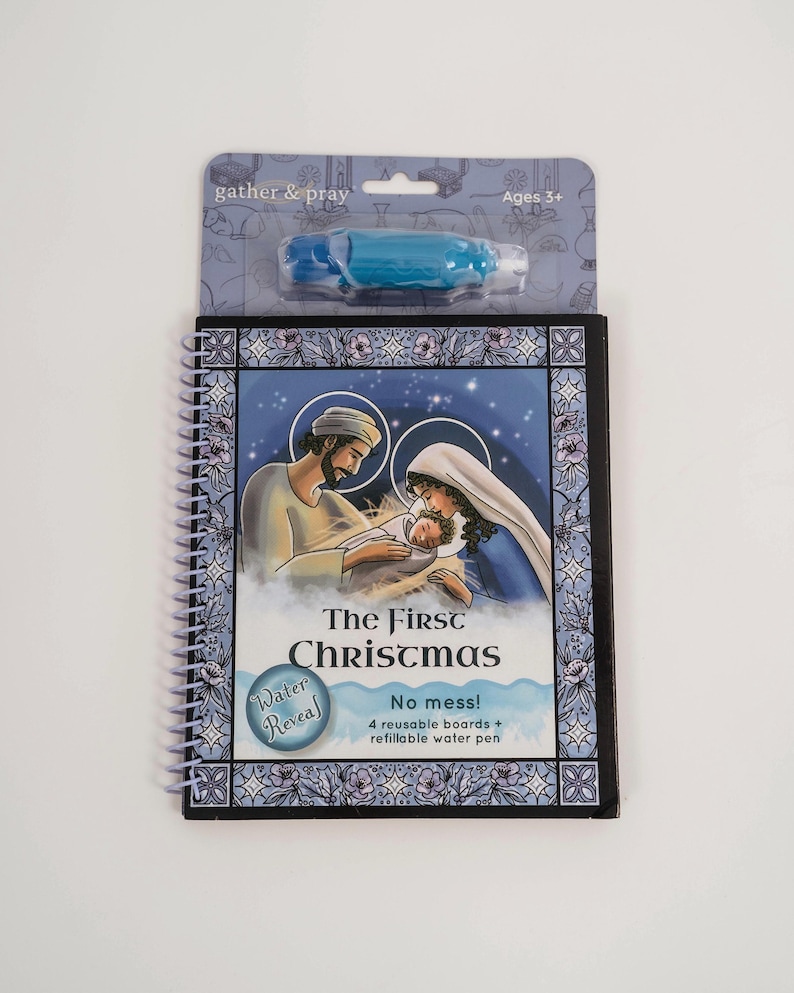 May include: A spiral-bound activity book titled "The First Christmas" with a blue and white border. The cover features an illustration of Mary, Joseph, and baby Jesus. Includes a blue water pen and four reusable boards. The packaging reads "gather & pray" and "Ages 3+".