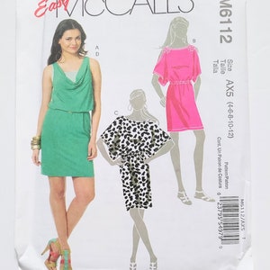 May include: McCall's sewing pattern M6112 featuring three dress designs. The pattern envelope shows a woman in a green dress, a pink dress, and a black and white patterned dress. Size AX5 (4-6-8-10-12).