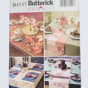 May include: A Butterick home sewing pattern, B4535, featuring various table setting designs. The cover showcases images of table runners, placemats, and tea settings with floral and patterned textiles. The pattern includes multiple table setting ideas.