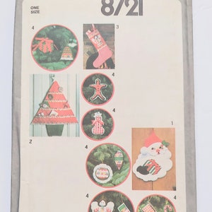 Könnte beinhalten: Simplicity 8721 Schnittmuster für Weihnachtsschmuck. Das Muster enthält Anweisungen zur Herstellung verschiedener festlicher Dekorationen, wie z. B. einen Weihnachtsmann, einen Weihnachtsbaum und Lebkuchenmänner. Einheitsgröße.