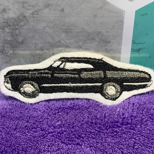 May include: Black embroidered patch of a classic car, a vintage sedan with a white background.