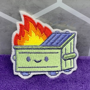 May include: A green embroidered patch of a smiling dumpster on fire. The flames are yellow, orange, and red. The dumpster has a blue lid.