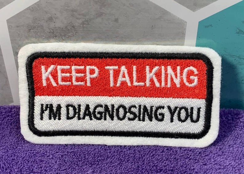 Puede incluir: Parche blanco bordado con ribete negro. El parche tiene un fondo rojo con el texto "KEEP TALKING" en blanco. La parte inferior del parche tiene un fondo blanco con el texto "I'M DIAGNOSING YOU" en negro.
