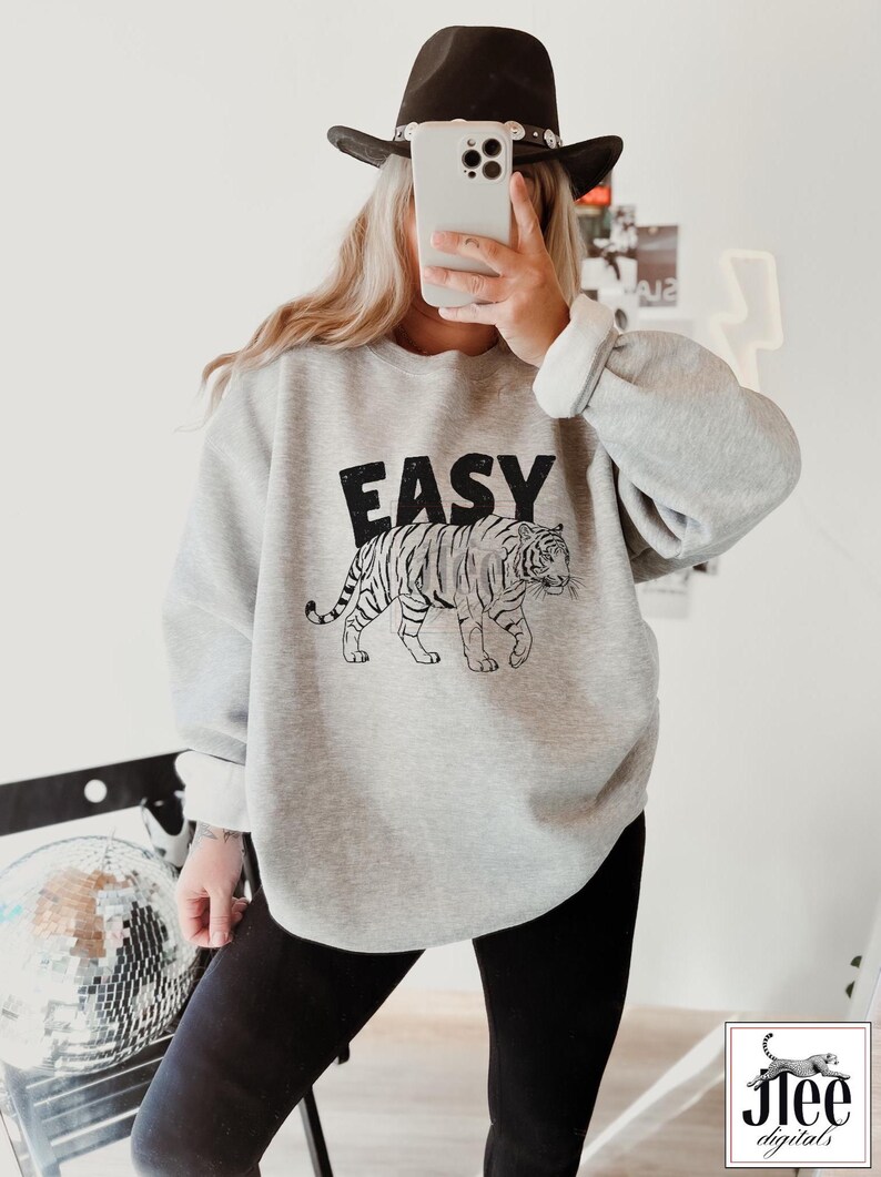 May include: A gray sweatshirt with a black and white tiger graphic and the word "EASY" printed on the front.