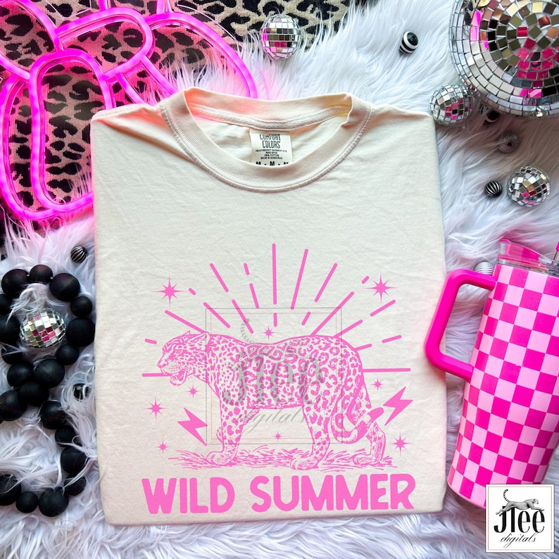 May include: A white t-shirt with a pink graphic of a leopard with a pink sunburst and lightning bolts. The text "WILD SUMMER" is printed in pink below the graphic.