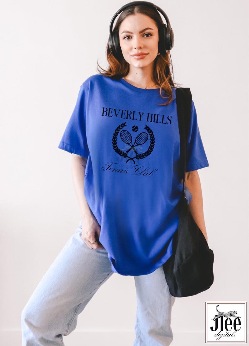 Puede incluir: Una camiseta azul real con un dise&ntilde;o gr&aacute;fico negro que dice "Beverly Hills Tennis Club" con un logotipo de raqueta de tenis y pelota.
