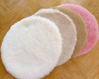 Könnte beinhalten: Ein Set aus vier runden, flauschigen Kunstfellmatten, die in einer kaskadierenden Reihe angeordnet sind. Die Matten haben eine weiche, zottelige Textur und sind in den Farben Weiß, Hellbeige, Hellbraun und Zartrosa gehalten, was einen Verlauf erzeugt.