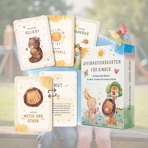 Könnte beinhalten: Ein Set von Affirmationskarten für Kinder mit Illustrationen von Bär, Sonne und Löwe. Die Box trägt die Aufschrift "Affirmationskarten für Kinder" und "44 liebevolle Karten für Mut, Freude und innere Stärke."