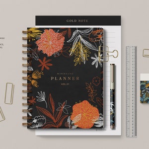 May include: A stationery mockup kit with a black and orange floral wirebound planner, a gold pen, a ruler, a gold binder clip, and a gold paper clip. The kit also includes a black and white floral eraser. The text "GOLD NOTE" and "WIREBOUND PLANNER VOL.01" is visible on the planner.