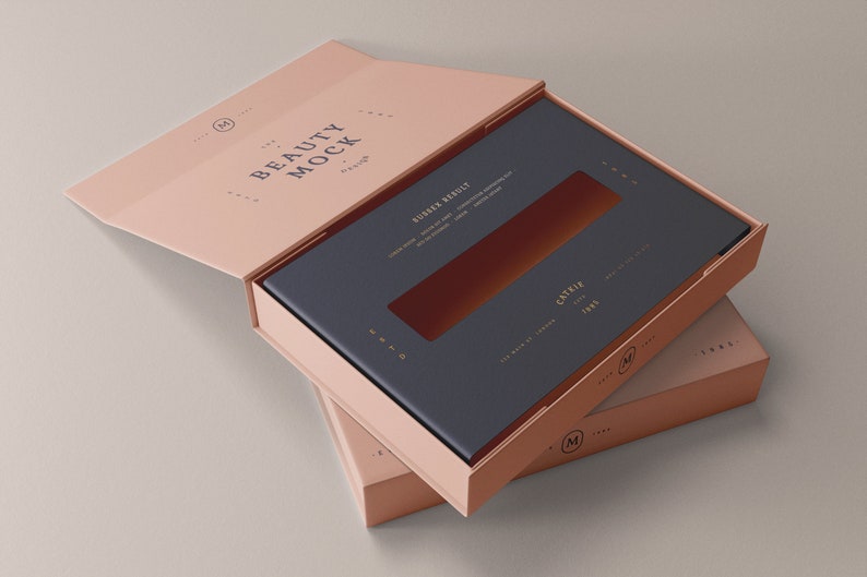 Puede incluir: Una caja rosa con una ventana recortada en la parte superior. La caja est&aacute; abierta y el interior est&aacute; forrado con un papel azul oscuro. La caja est&aacute; etiquetada con "Beauty Mock" y "Castile" en una fuente dorada.