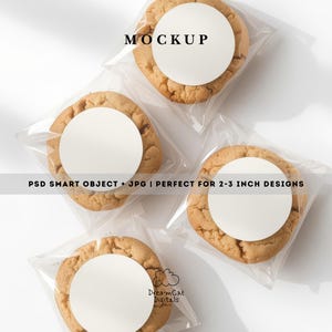 May include: Four golden-brown cookies individually wrapped in clear plastic bags, each featuring a blank white circular label on top. The image includes the text MOCKUP and PSD SMART OBJECT + JPG | PERFECT FOR 2-3 INCH DESIGNS and DreamCat Digitals.