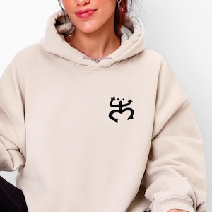 Minimalist Coquí Taíno Frog hoodie in sand color with black design