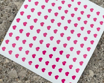 May include: White sheet of paper with a repeating pattern of pink hearts.