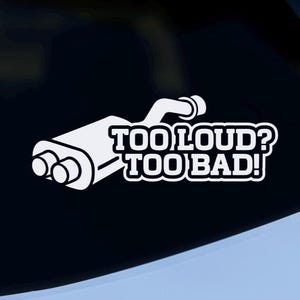 May include: White decal of a car exhaust with the text "TOO LOUD? TOO BAD!" on the rear window of a white car. The exhaust graphic is a stylized representation of a muffler.