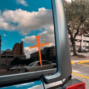 Orange three nail cross vinyl decal on Jeep rear window, Christian faith car decal with rustic nail cross design