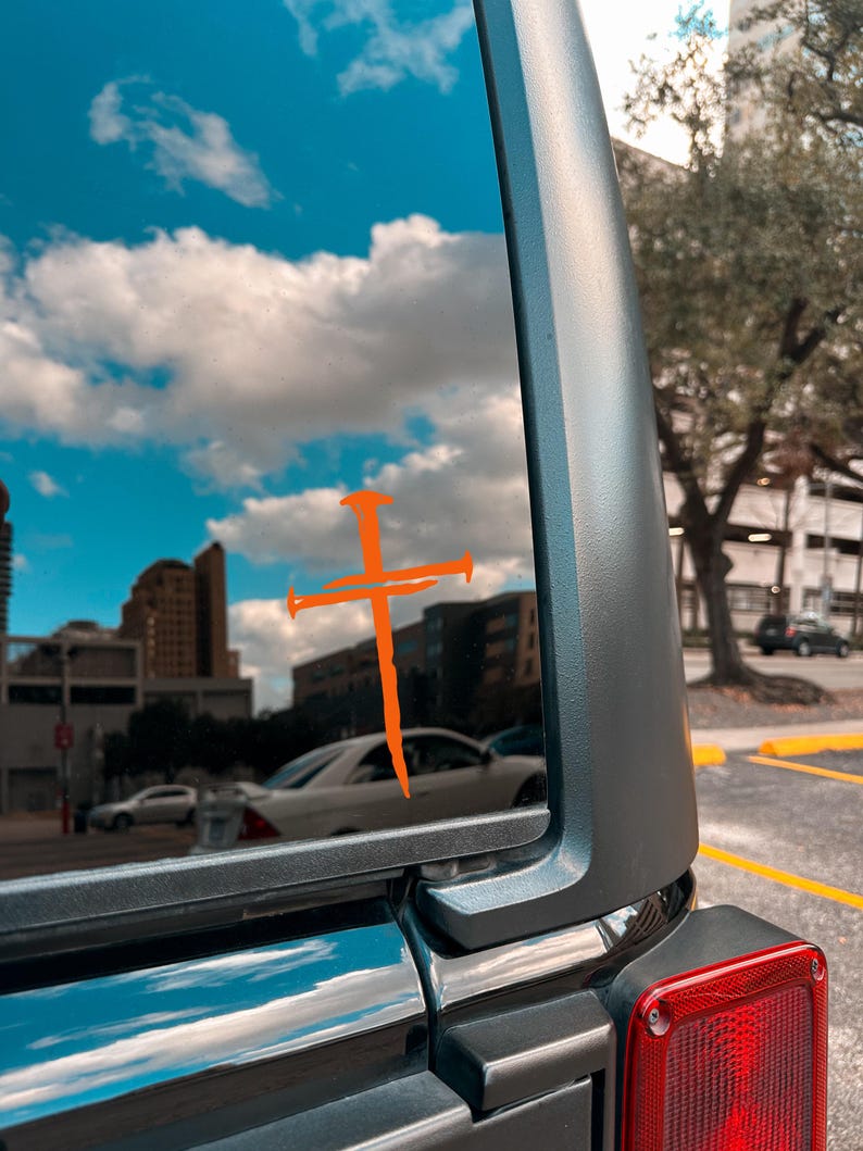 Orange three nail cross vinyl decal on Jeep rear window, Christian faith car decal with rustic nail cross design