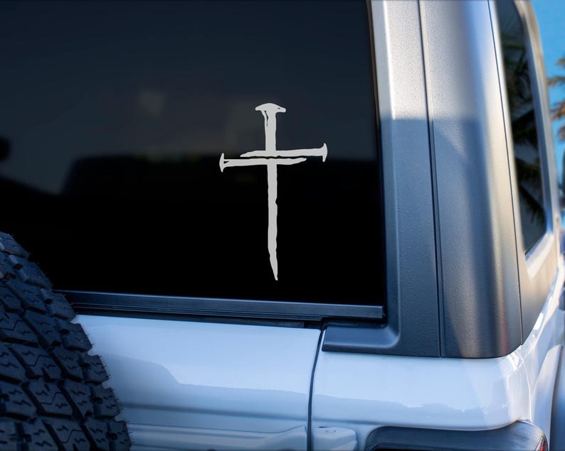 Three nail Christian cross vinyl decal in white displayed on the rear window of a Jeep, minimalist religious car window sticker