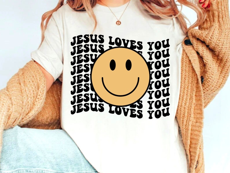 May include: White t-shirt with a black and yellow smiley face and the text "JESUS LOVES YOU" repeated in a retro font.