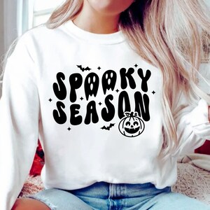 May include: White sweatshirt with a black graphic print that says "Spooky Season" with a pumpkin and bats.