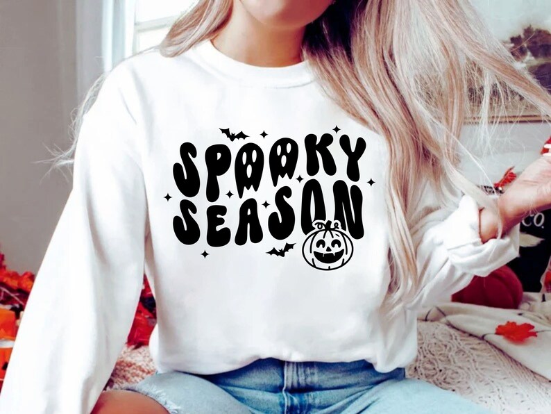 May include: White sweatshirt with a black graphic print that says "Spooky Season" with a pumpkin and bats.