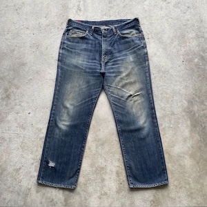K&ouml;nnte beinhalten: Verblasste blaue Jeans mit klassischem F&uuml;nf-Taschen-Design. Die Jeans weisen Gebrauchsspuren auf, einschlie&szlig;lich Abnutzung und einem kleinen Riss am linken Bein. Die Jeans haben einen geraden Bein-Schnitt und einen Knopf- und Rei&szlig;verschluss.