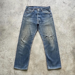 Puede incluir: Vaqueros de mezclilla azul descolorido con bragueta de botones y rodilla desgastada. Los vaqueros tienen un diseño clásico de cinco bolsillos y muestran signos de desgaste. La mezclilla tiene un lavado vintage.