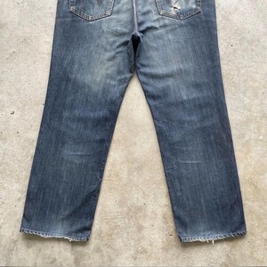 K&ouml;nnte beinhalten: Verblasste blaue Jeans mit klassischem F&uuml;nf-Taschen-Design. Die Jeans weisen Gebrauchsspuren auf, mit abgenutzten Details und einem eingetragenen Aussehen. Die Ges&auml;&szlig;taschen haben eine dekorative Naht.