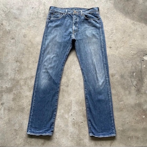 May include: Faded blue denim jeans with a button fly. The jeans have a classic five-pocket design and a straight leg fit. The denim has a worn appearance with subtle fading and whiskering.