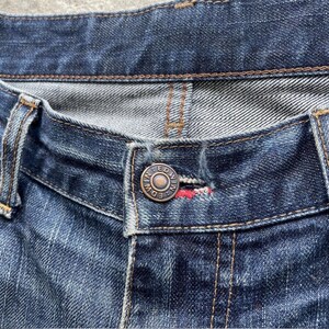 K&ouml;nnte beinhalten: Nahaufnahme einer blauen Jeans. Die Jeans hat einen Knopfverschluss mit dem Markennamen "EDWIN" auf dem Knopf. Die N&auml;hte sind sichtbar, und der Stoff hat ein abgenutztes Aussehen.