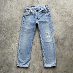 May include: Light blue denim jeans with a faded wash and distressed details. The jeans have a classic five-pocket design, a button and zipper closure, and a straight leg fit. The jeans show signs of wear and tear.